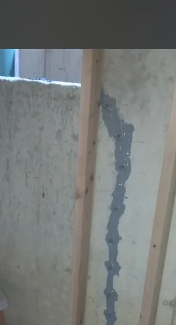 Concrete wall with a visible vertical crack filled with sealant.