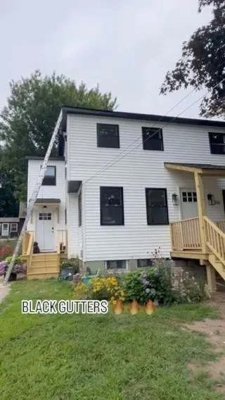 A two-story white house with new black windows and gutters, featuring two front entrances with light wood stairs.