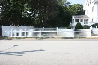 White vinyl picket fence along a residential street