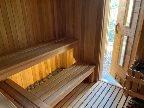 Custom home sauna with integrated benches, under-lighting, and stone detailing