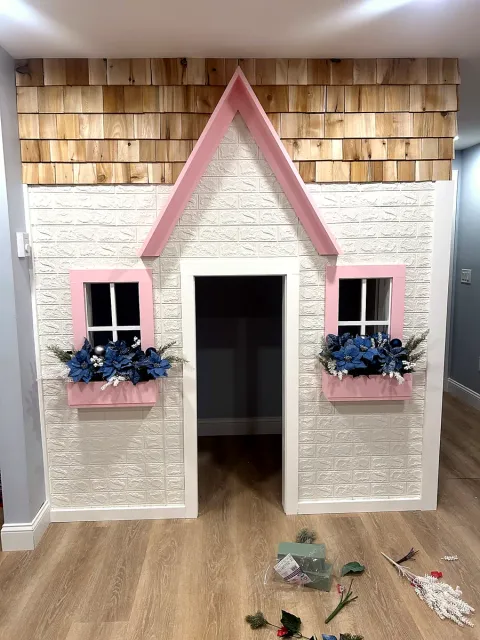 Indoor playhouse feature wall with cedar shingles, window trim and a peaked roof line