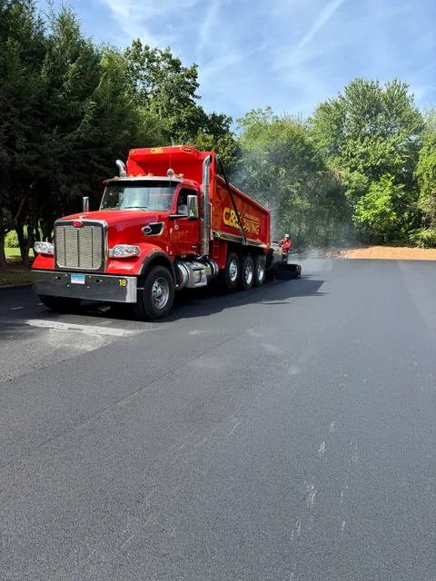 A professional paving truck distributing hot mix asphalt for a smooth driveway installation in Watertown.