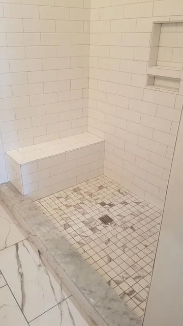 Tiled walk-in shower with a built-in bench, wall niche and mosaic floor