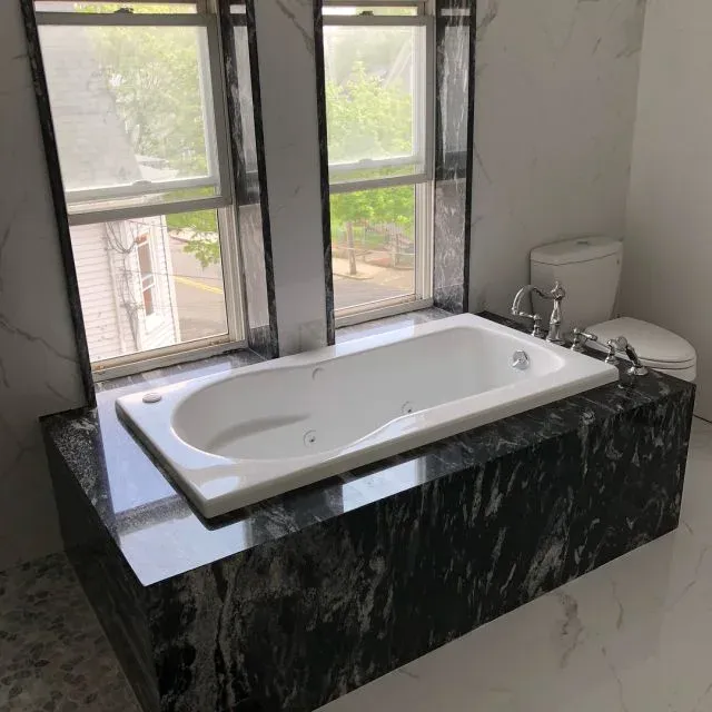 Bathtub surround in veined black granite with white marble walls