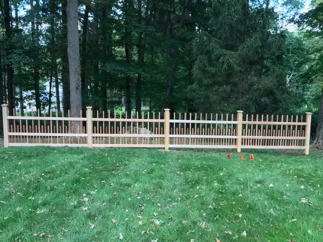 A wooden fence is sitting in the middle of a lush green field.