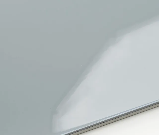 Close-up of a metallic surface, possibly a part of a machine or appliance, with a smooth, reflective finish and a slight beveled edge.