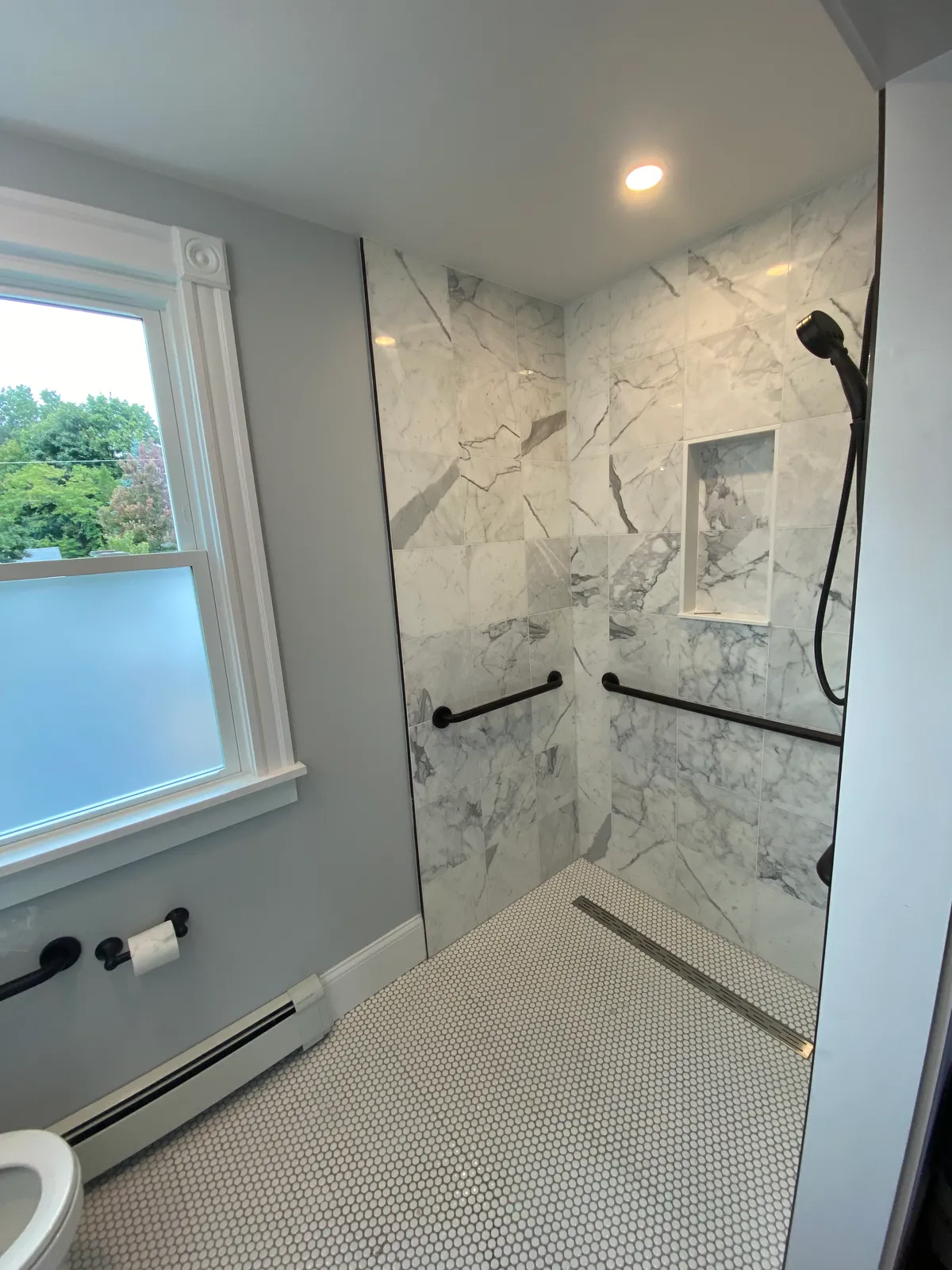 Bathroom shower with marble tile and black fixtures