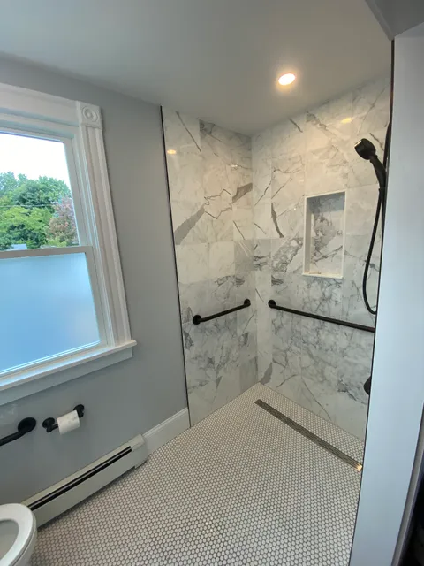 Bathroom shower with marble tile and black fixtures