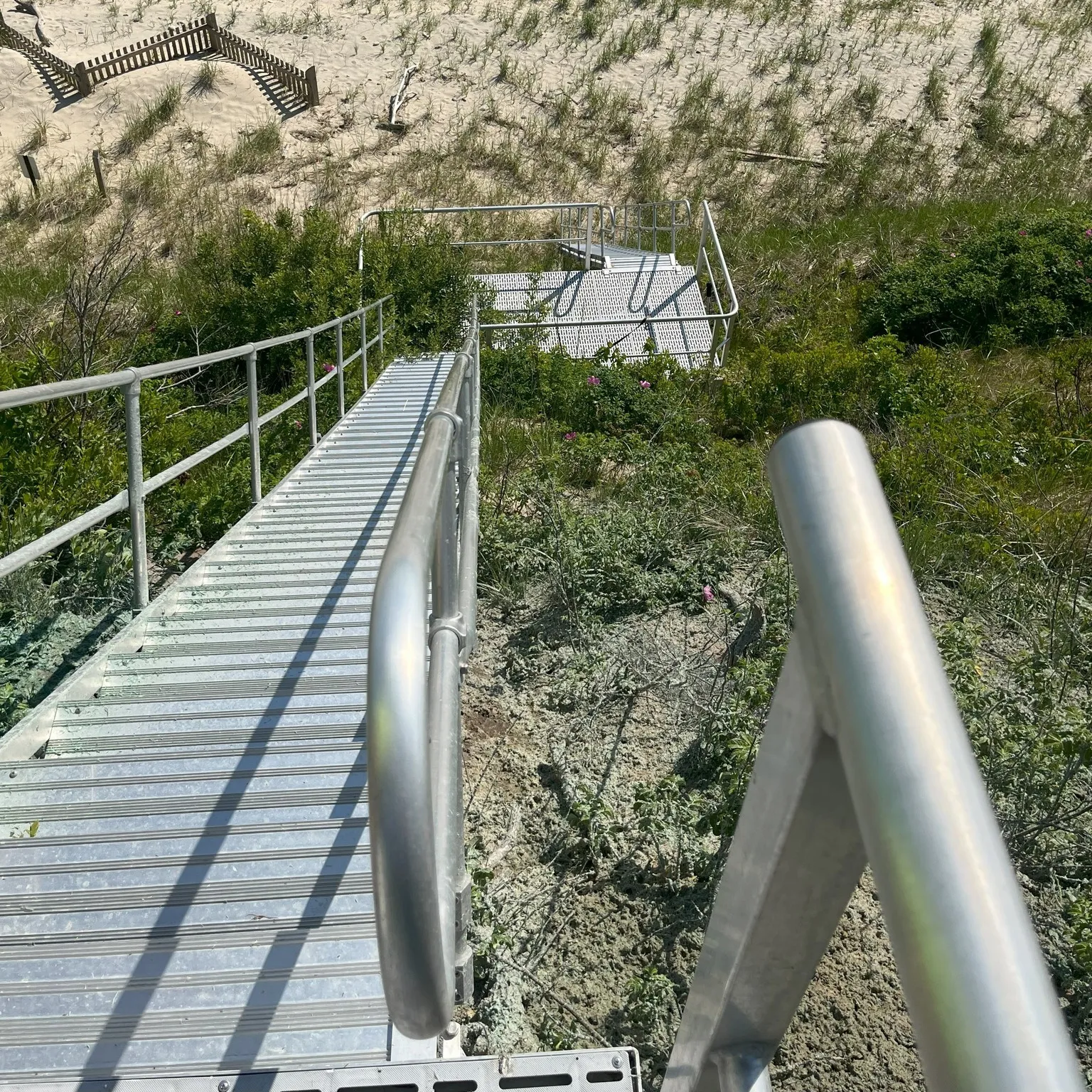 Beach access stairs leading down sandy coastal slope