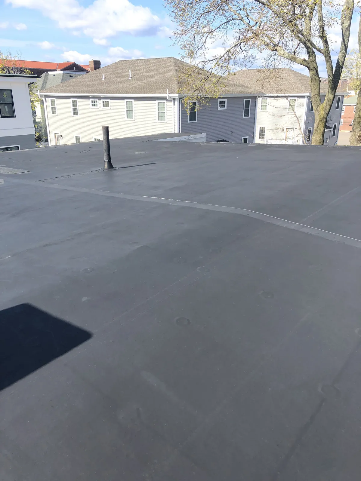 Completed black EPDM flat roof with chimney flashing installed by Storm King Roofing in Waltham, MA