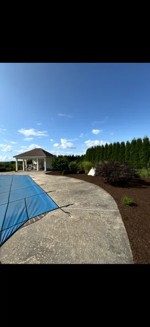 A swimming pool with a blue cover on it and a gazebo in the background.