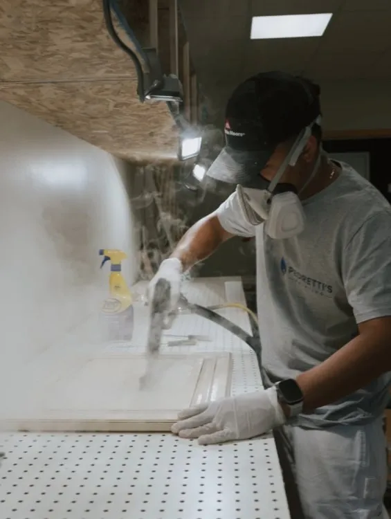 Pedretti's Cabinet Co. team member in protective gear preparing and finishing a cabinet door