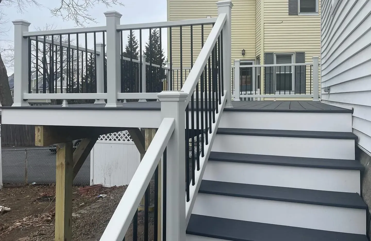 A deck with stairs leading up to it and a house in the background.