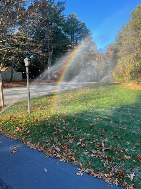 A residential home with sprinklers and an irrigation system installed by BC Irrigation that shows a rainbow across the mist