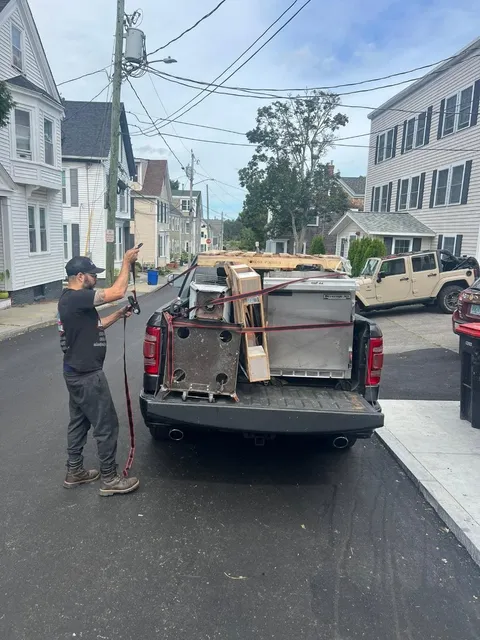 Alpha Haul crew strapping a commercial cooler into a truck bed