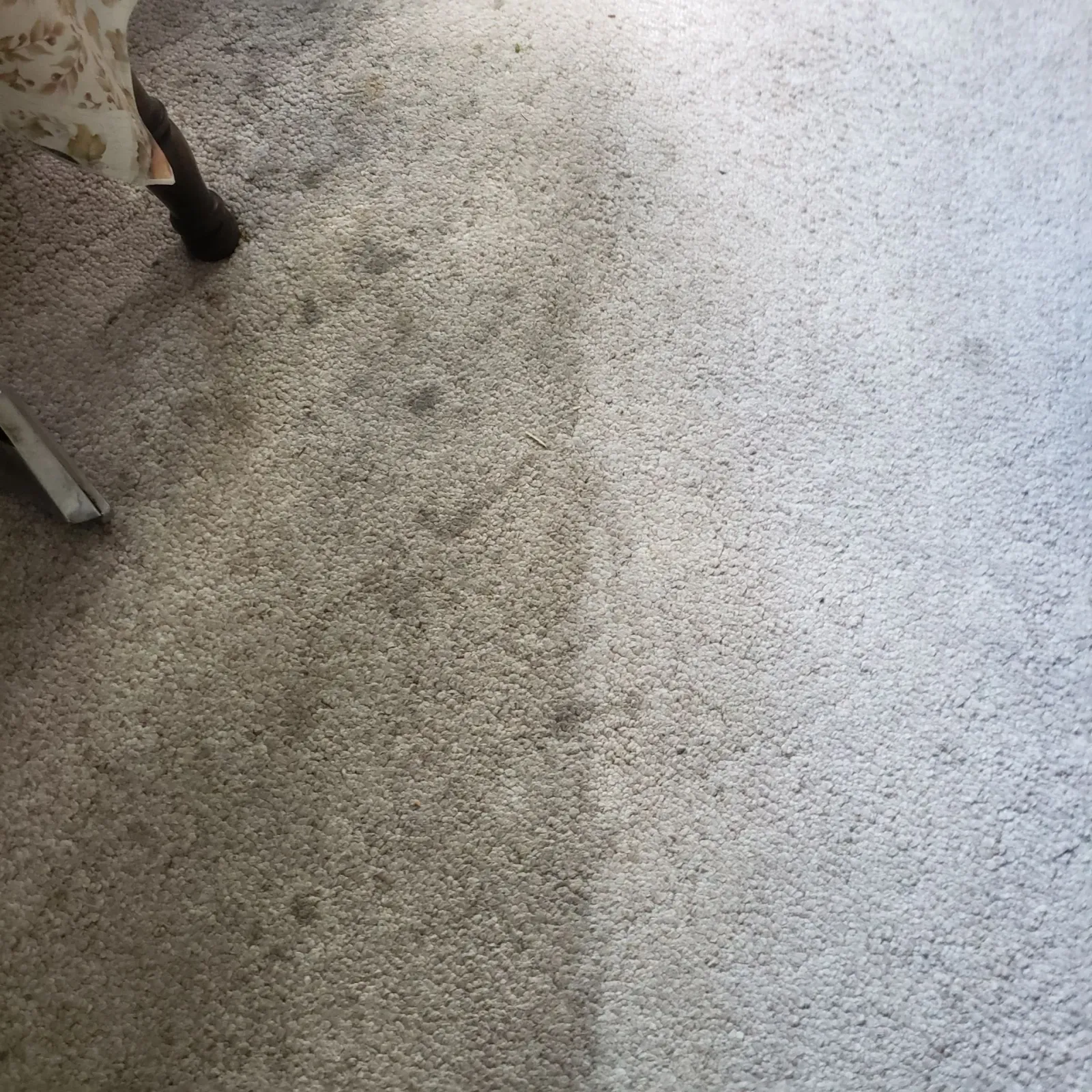 a close up of a carpet with a chair in the background