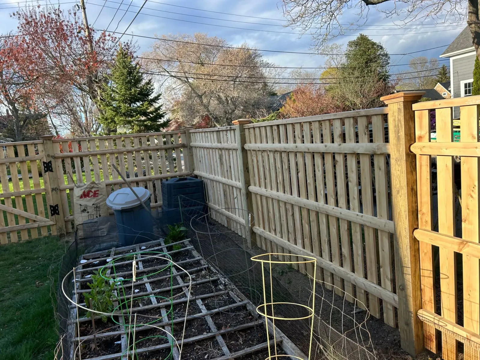 A wooden fence surrounds a garden with plants growing in it.