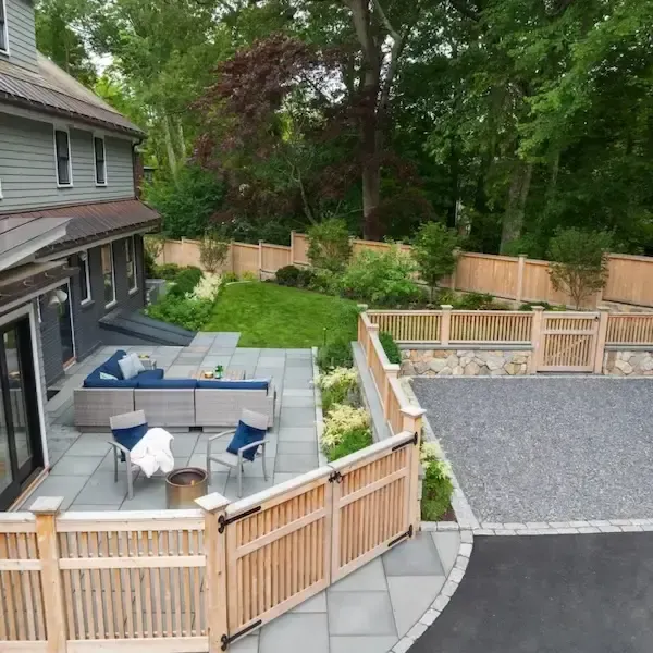 luxury outdoor space with a gravel driveway, a new wooden fence, and stone patio.