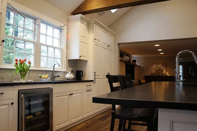 A kitchen with white cabinets and a black counter top