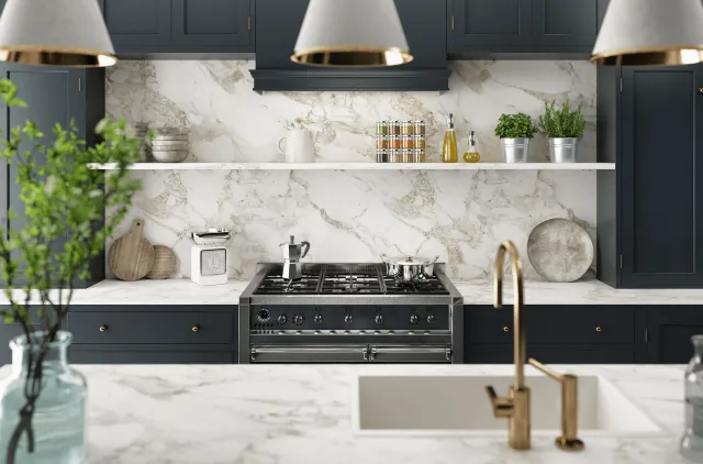Kitchen with veined white stone countertop and matching full-height backsplash, navy cabinets, black range and brass faucet