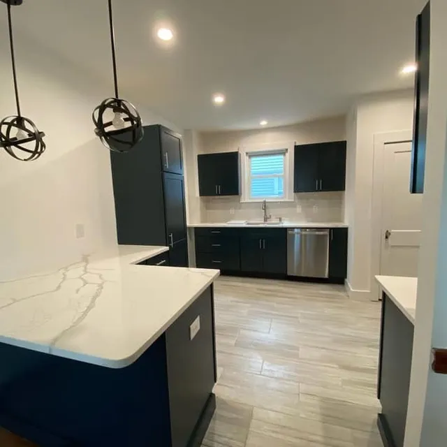 Finished kitchen remodel with navy cabinetry and quartz counters