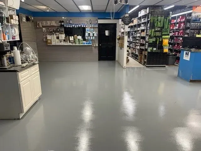 Brightly lit retail store interior with gray flooring, shelves of products, and counter space.