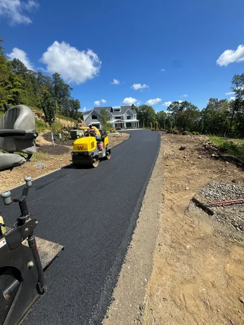 Yellow utility vehicle on a newly paved driveway in a sunny landscaped yard
