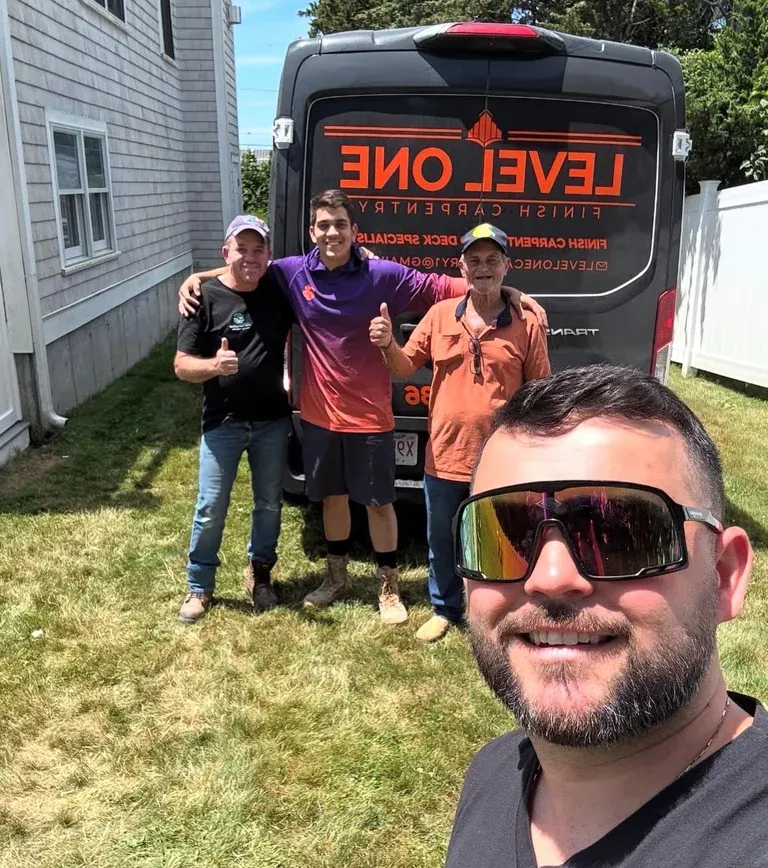 Four men posing in front of a red and black Level One food truck in a residential yard on a sunny day
