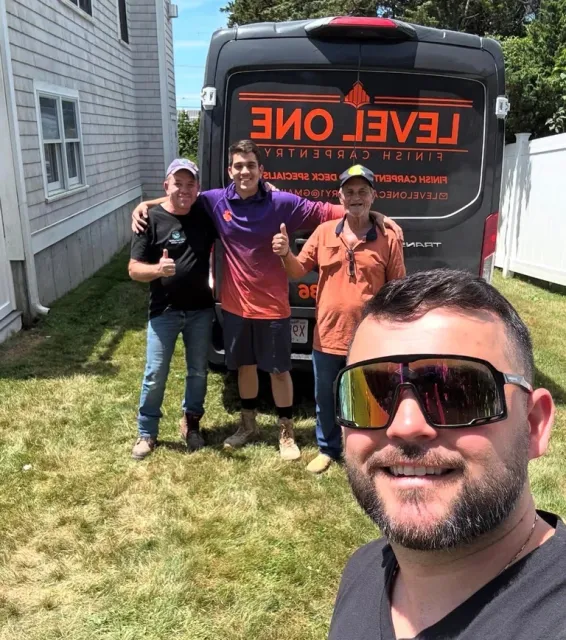 Four men posing in front of a red and black Level One food truck in a residential yard on a sunny day