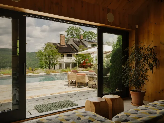 View from inside the pool house toward the terrace seating area and pool
