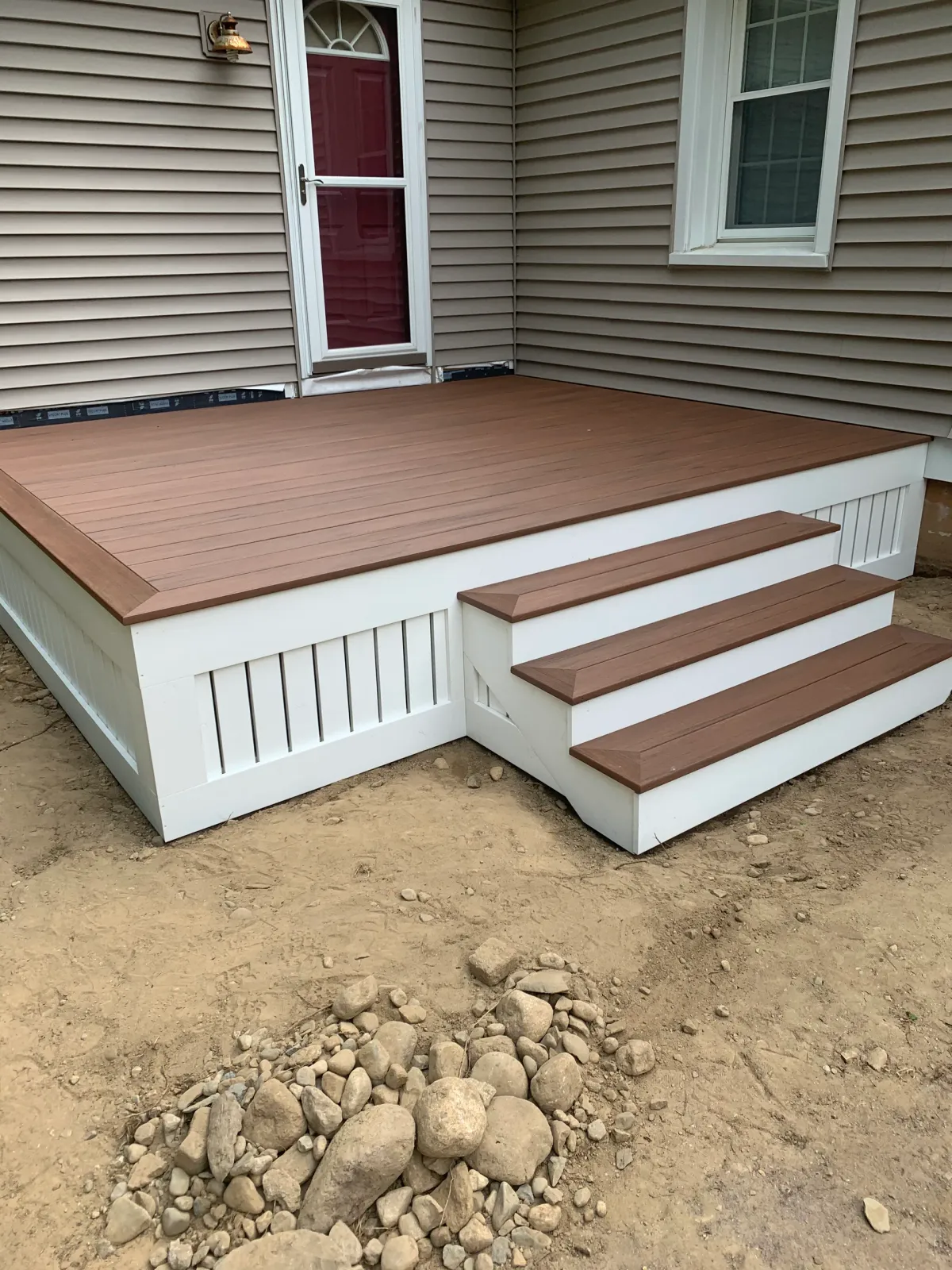 A wooden deck with stairs is in front of a house.