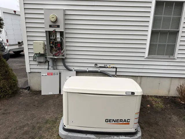 Generac whole-home generator installed alongside electrical service panel on a Taunton, MA residence
