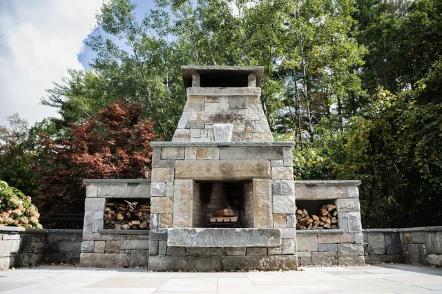 outdoor stone patio with fireplace and stair lighting