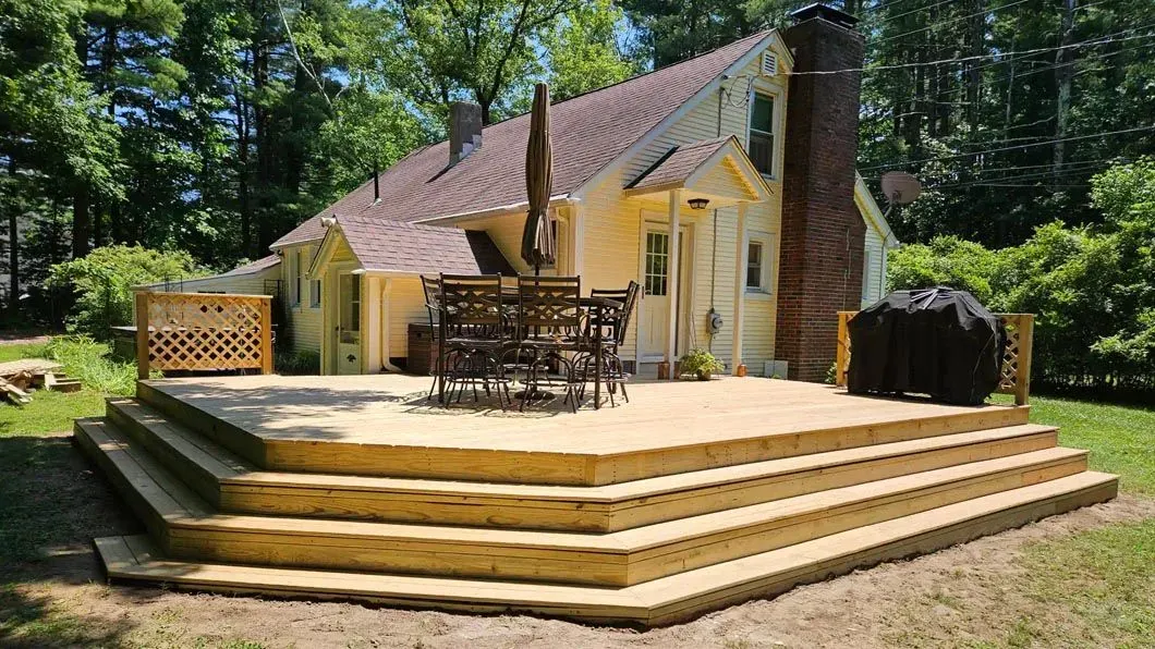 There is a large wooden deck in front of a house.