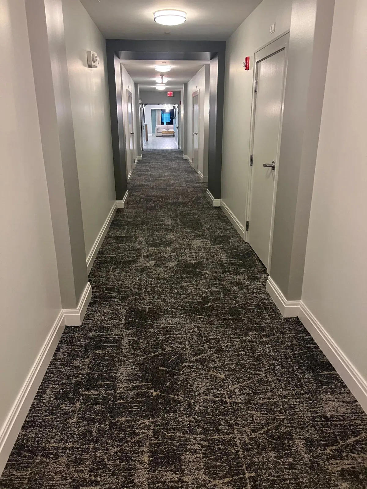A long hallway with a black carpet and white walls.