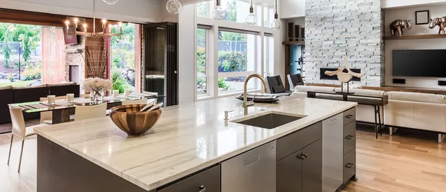 Kitchen island with built-in sink topped with beige stone with horizontal gray veining