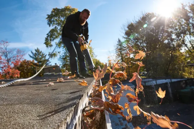 Clearing fall leaves and debris from a roof and gutters