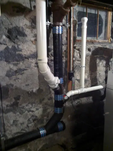 Cast-iron stack tied into new PVC in a fieldstone basement