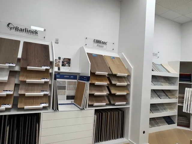 Display of sample flooring and wall materials in a showroom, with shelves of panels and swatches.