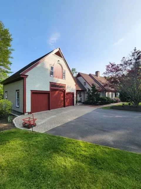 Suburban house with red garage doors, driveway, and green lawn under a blue sky