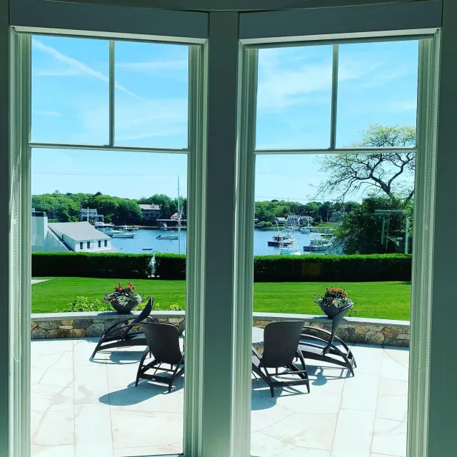 Two windows with a view of a patio with chairs and boats