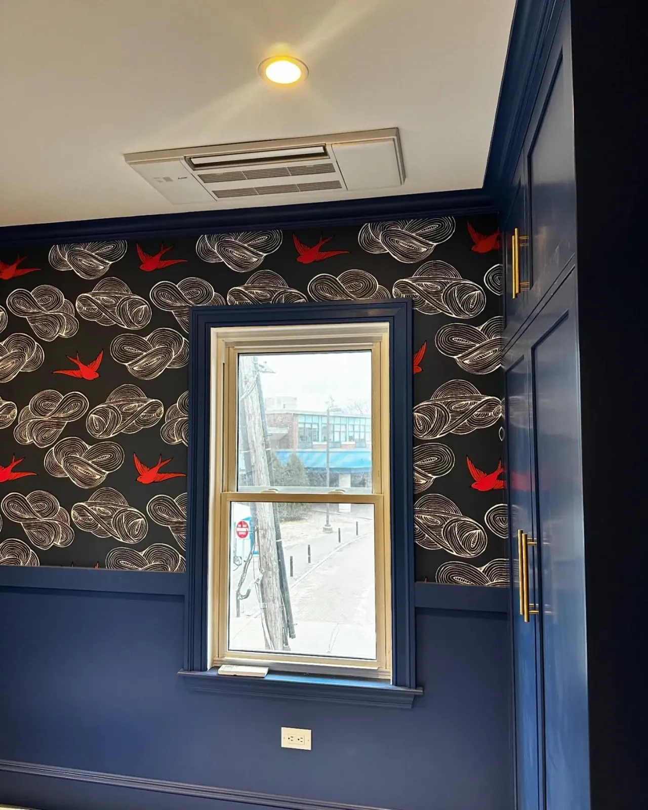 a room with a window and a black wall with birds on it