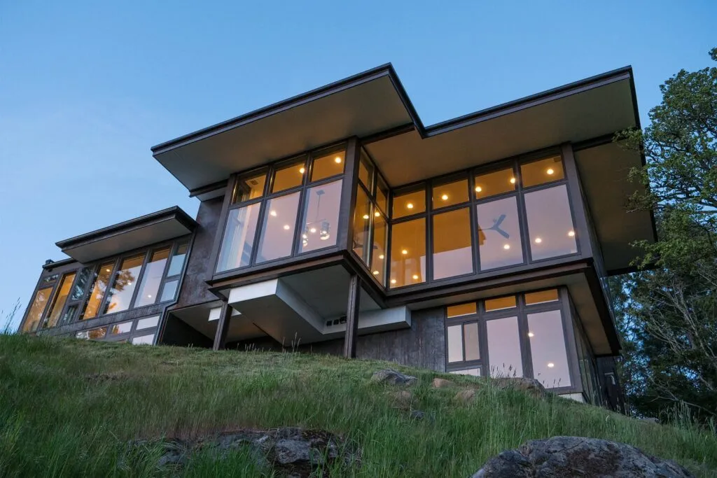 large house on top of a hill with large glass windows