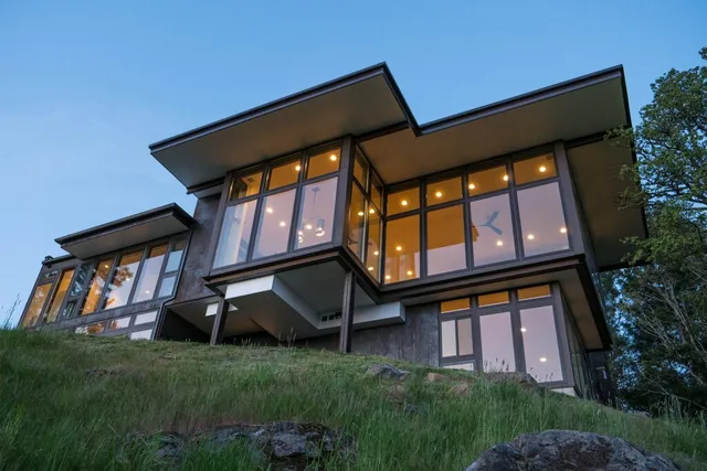 large house on top of a hill with large glass windows