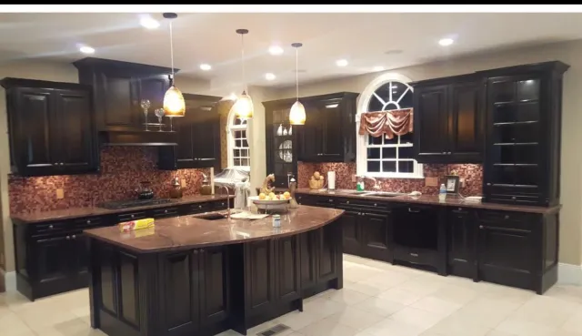 Spacious kitchen with dark wood cabinets, granite island, pendant lights, and tiled backsplash.