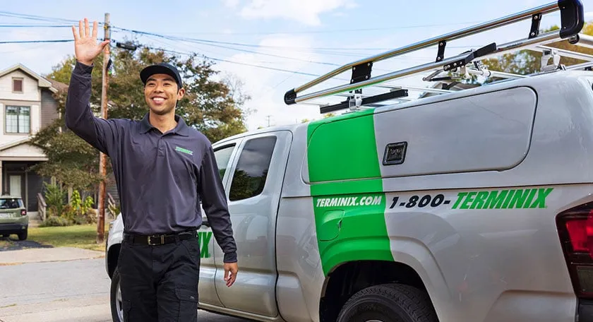Pest control tech waving his hand in front of a Terminix truck