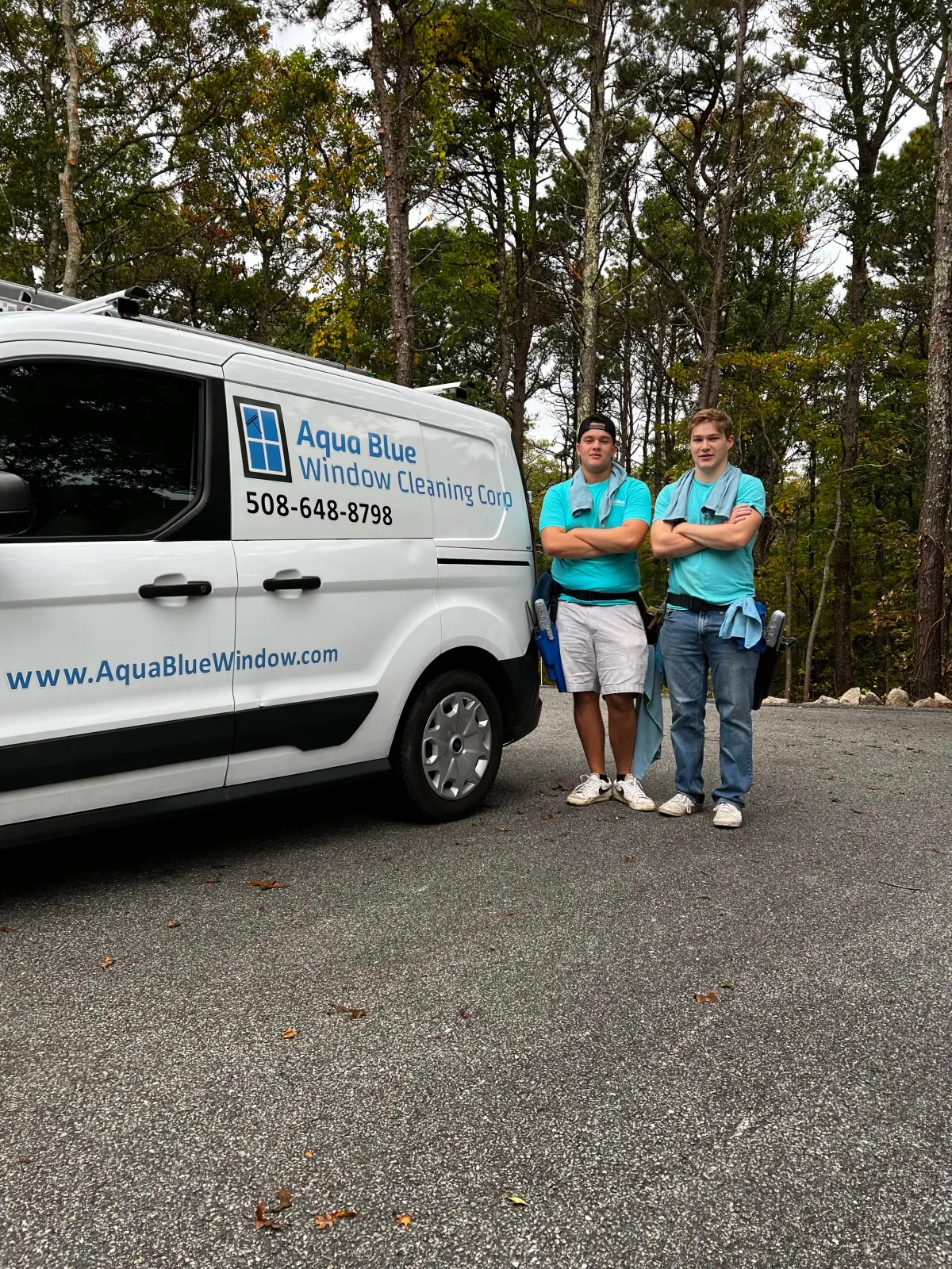 Two young men in blue shirts next to van