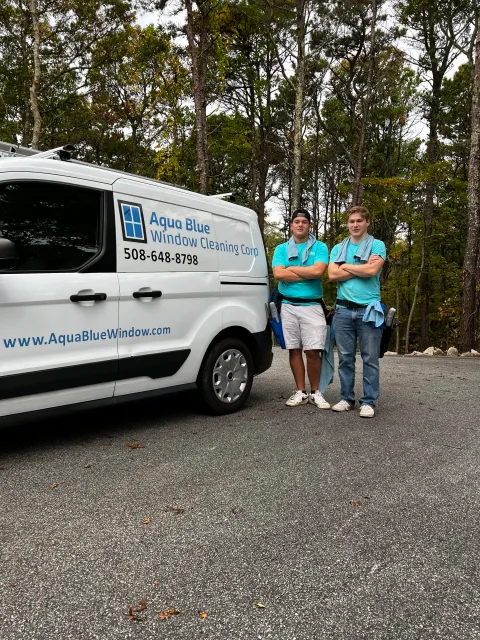 Two young men in blue shirts next to van