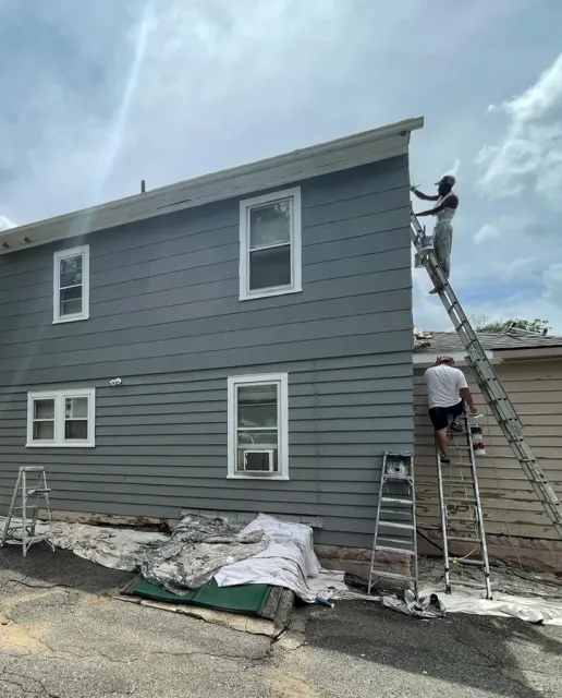Home painting in progress on a grey house exterior.