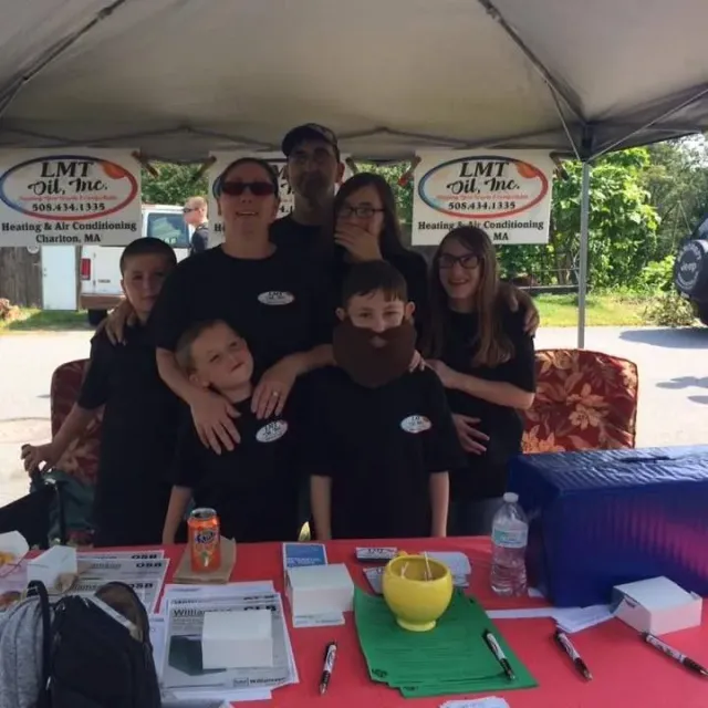 A group of people posing for a picture under a tent that says lmt